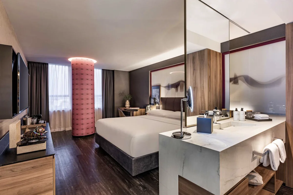 A Standard Room with a king bed, marble vanity and a window onto the city