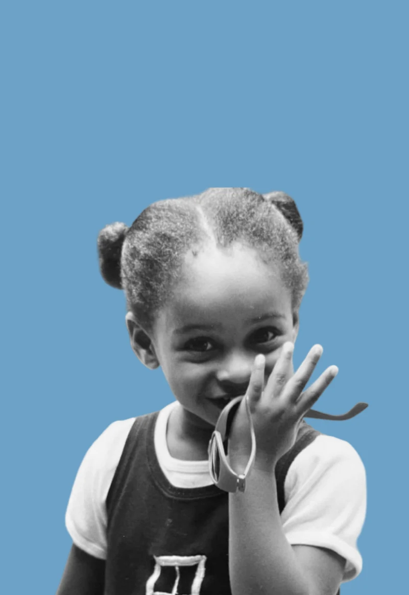 Ciera as a little kid with her hair in puffs, smiling and waving at the camera