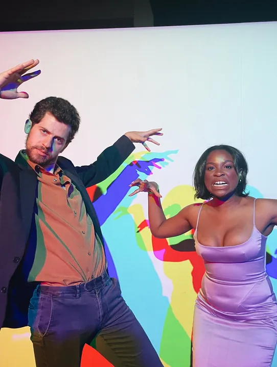 Cooper and Ciera dancing in front of a rainbow backdrop