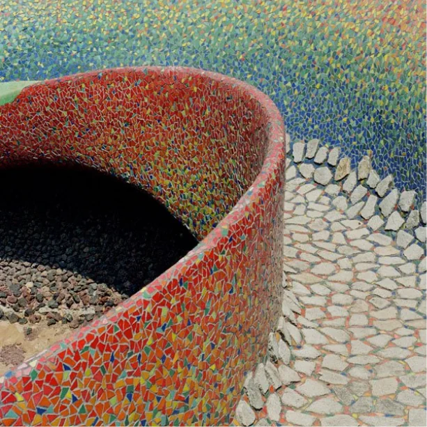 A curved, mosaic-tiled wall beside a pebbled path